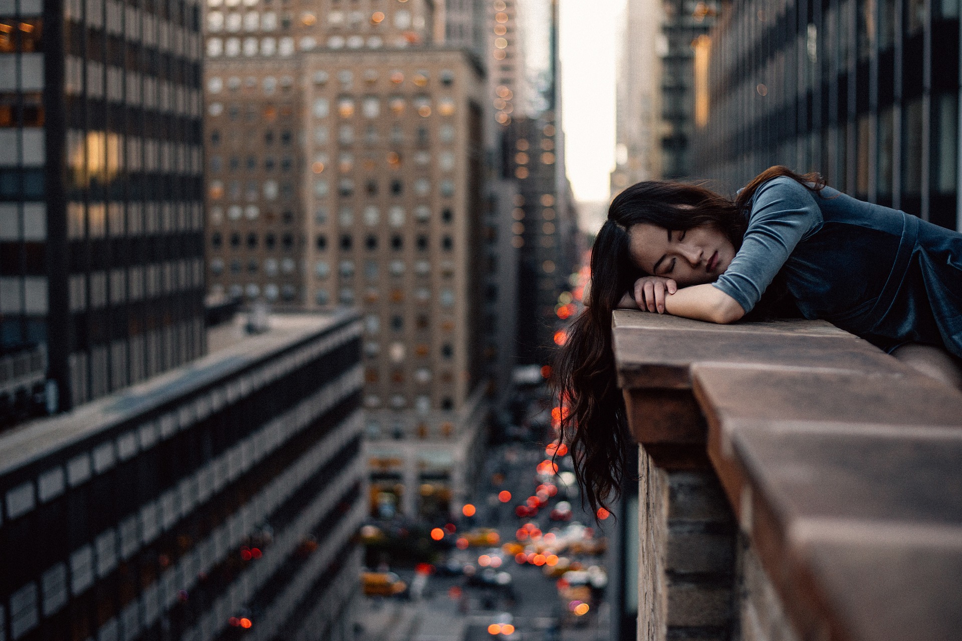 Image of young woman resting her head on balcony overlooking busy streets