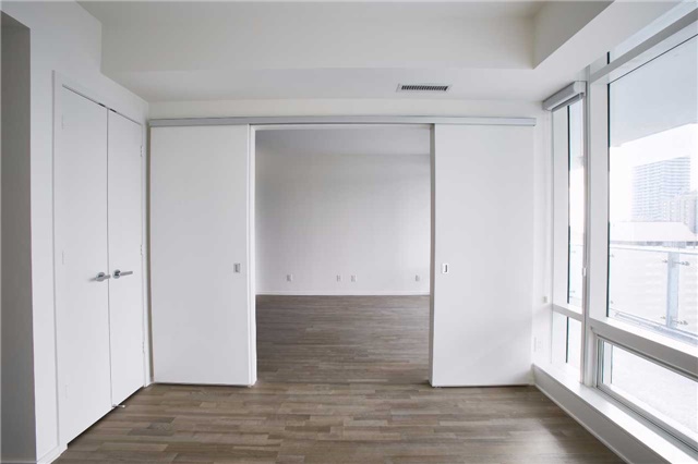 Rear view of 1 Bloor Unit 3109 master bedroom with doors open. Much as the rest of the condo, the doors are white while the hardwood floors are brown.