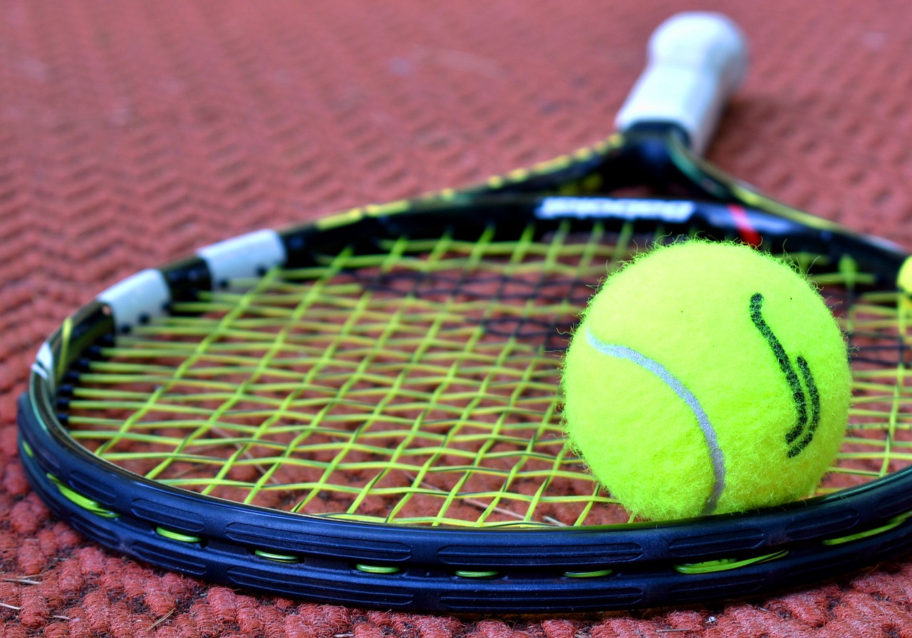 Another close up image, this one shows a tennis ball and racket and a purple background.