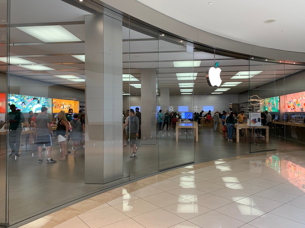 Apple storefront with glass displays and customers.