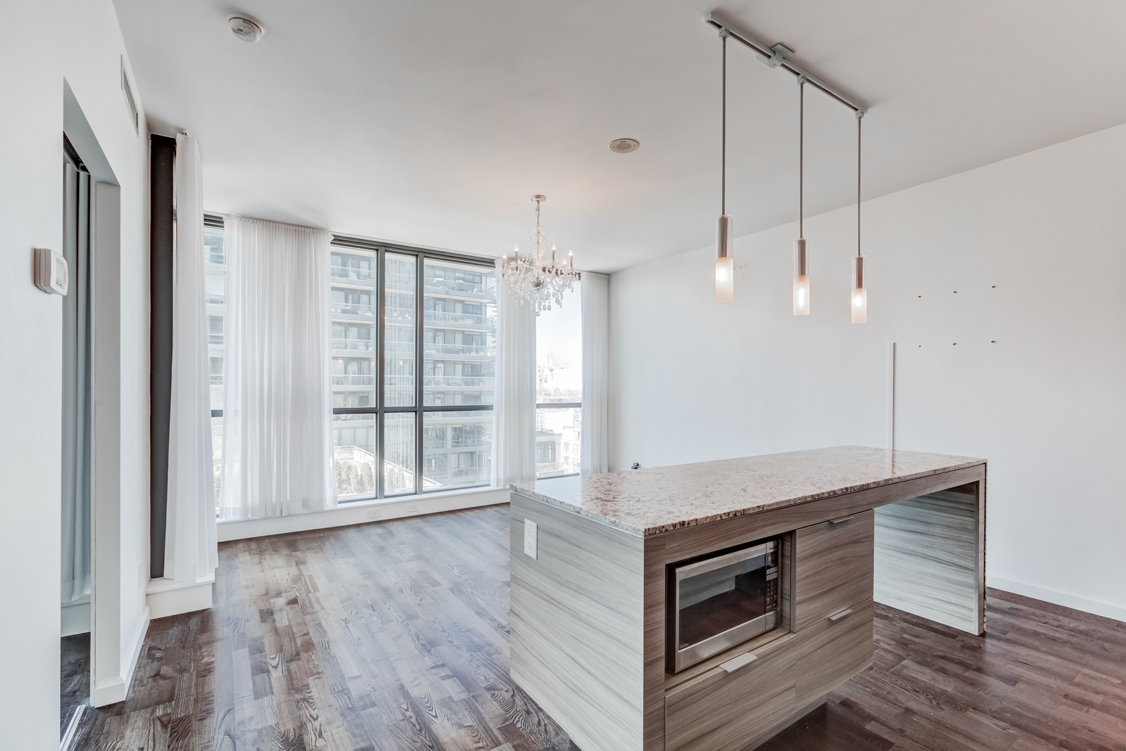  Brightly lit condo living room and kitchen island with hanging lights.