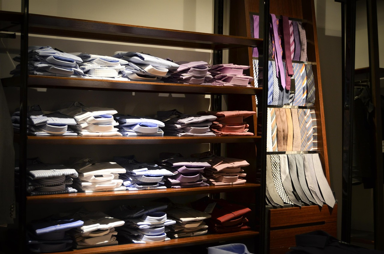  Shelves with neatly folded men's shirts and ties in many colours.