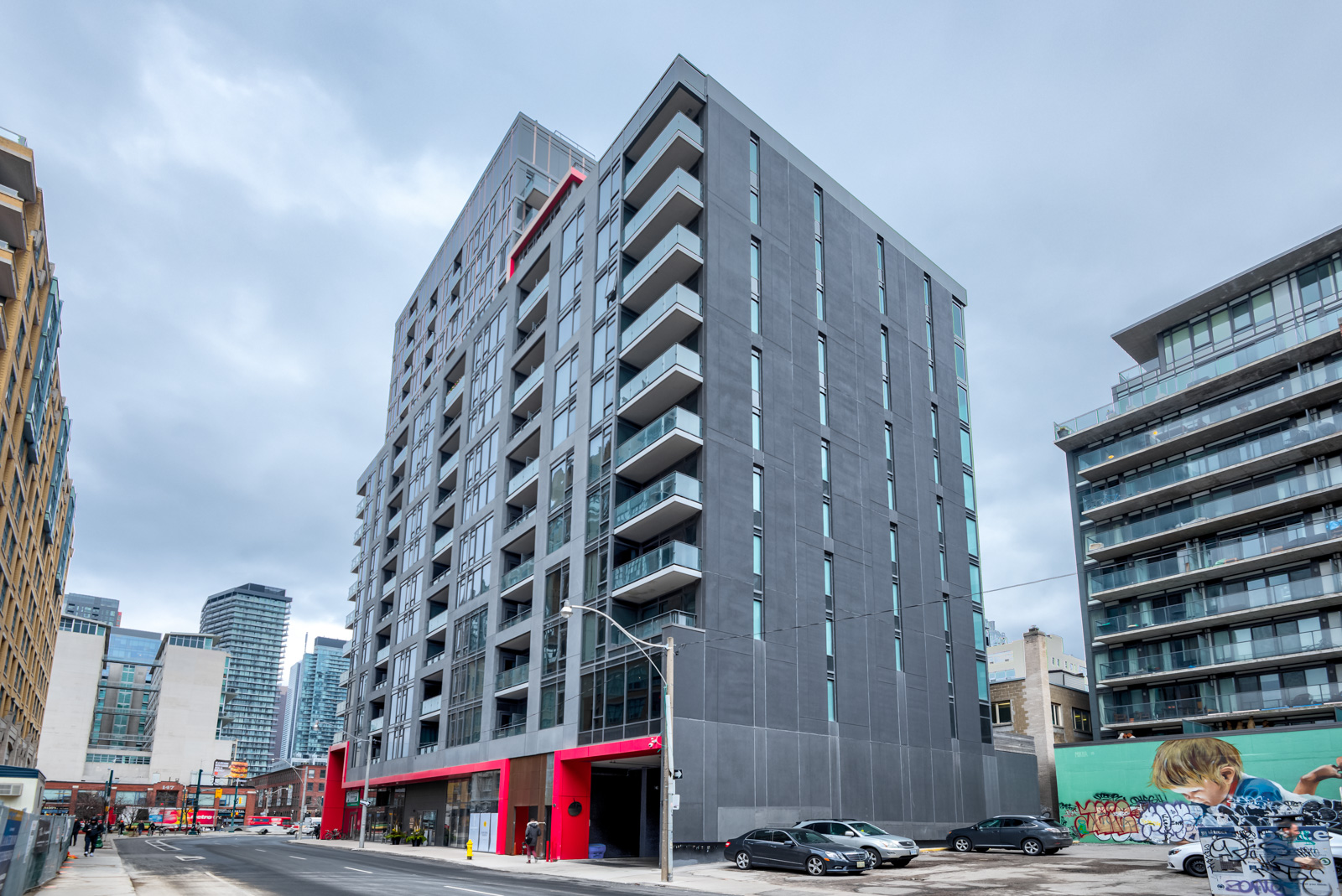 Street view of Fabrik Condos, a dark gray building with bright red accents on 435 Richmond St W PH 101.
