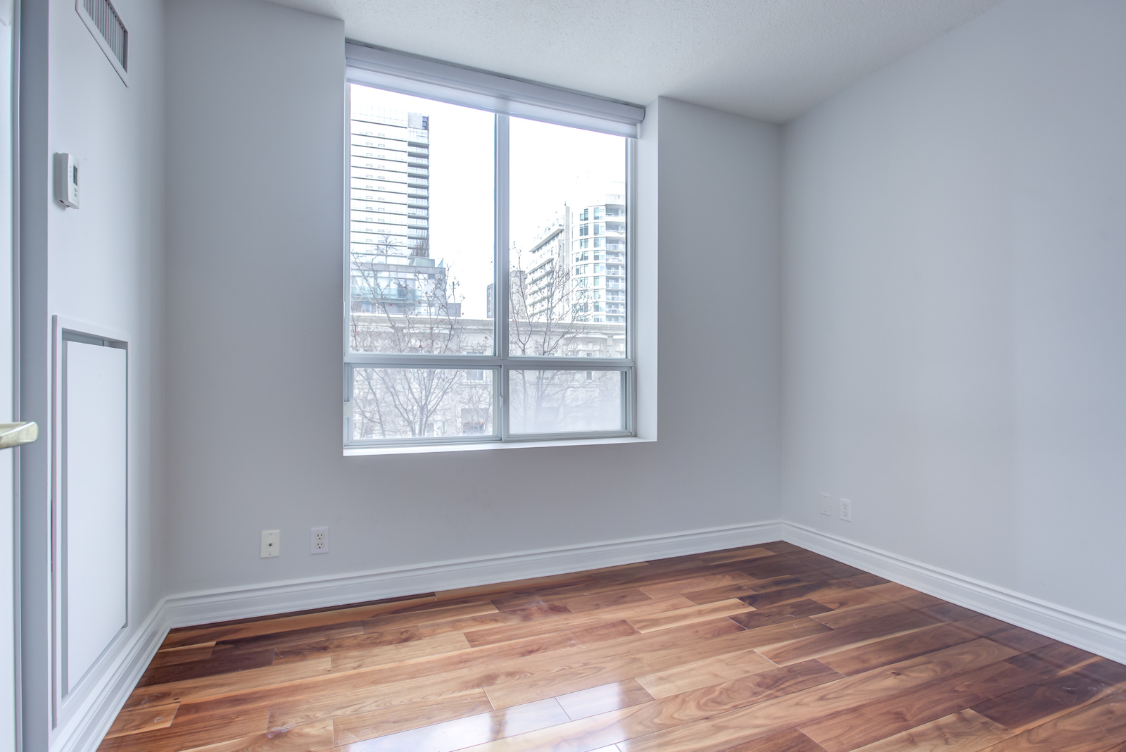 Bedroom with newly-painted gray walls and shiny dark brown hardwood floor at 20 Collier St Unit 408.