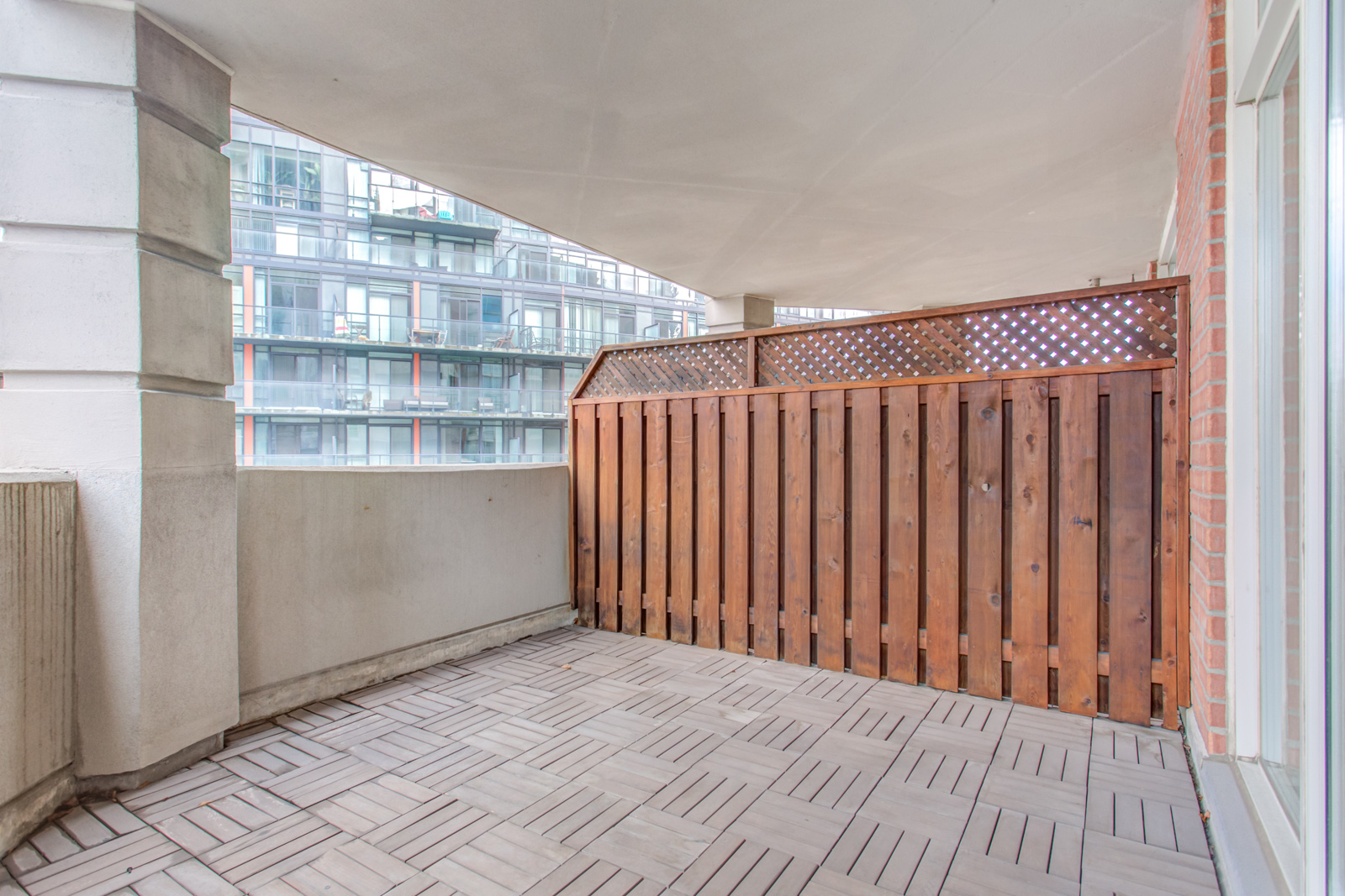 Balcony and deck of 20 Collier St Unit 408 with tiled floors and red wood fence.