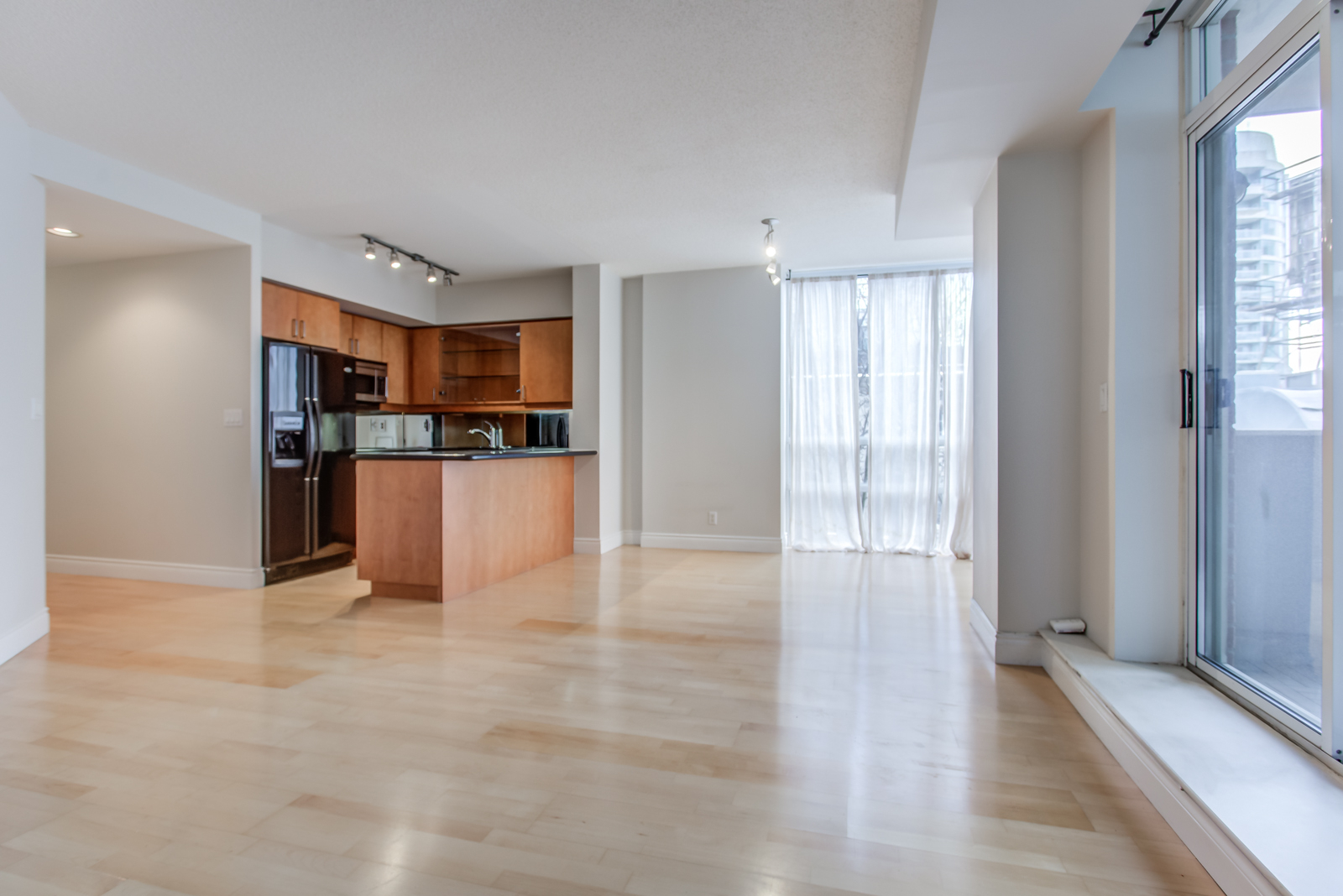 Empty living, dining & kitchen area of 20 Collier St Unit 408 with shiny hardwood floors.
