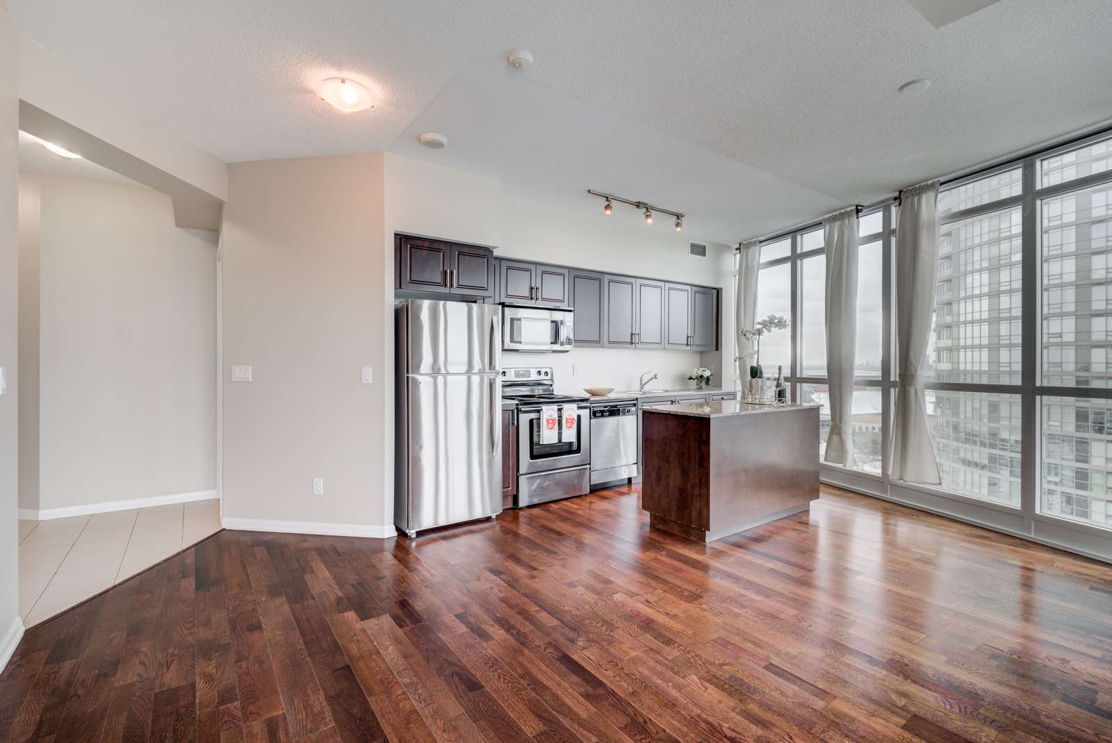 Shot of 215 Fort York Blvd Unit 2310 open-concept living and dining room with dark hardwood floors.