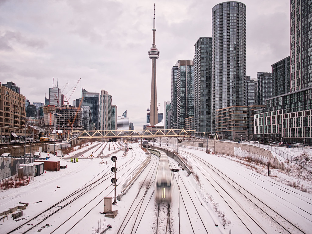 Toronto rail-yard with CN Tower and condos in distance covered in snow.