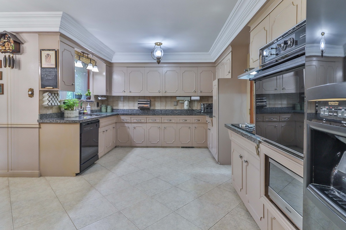 Kitchen with crown moulding, black granite counters and stone floors.