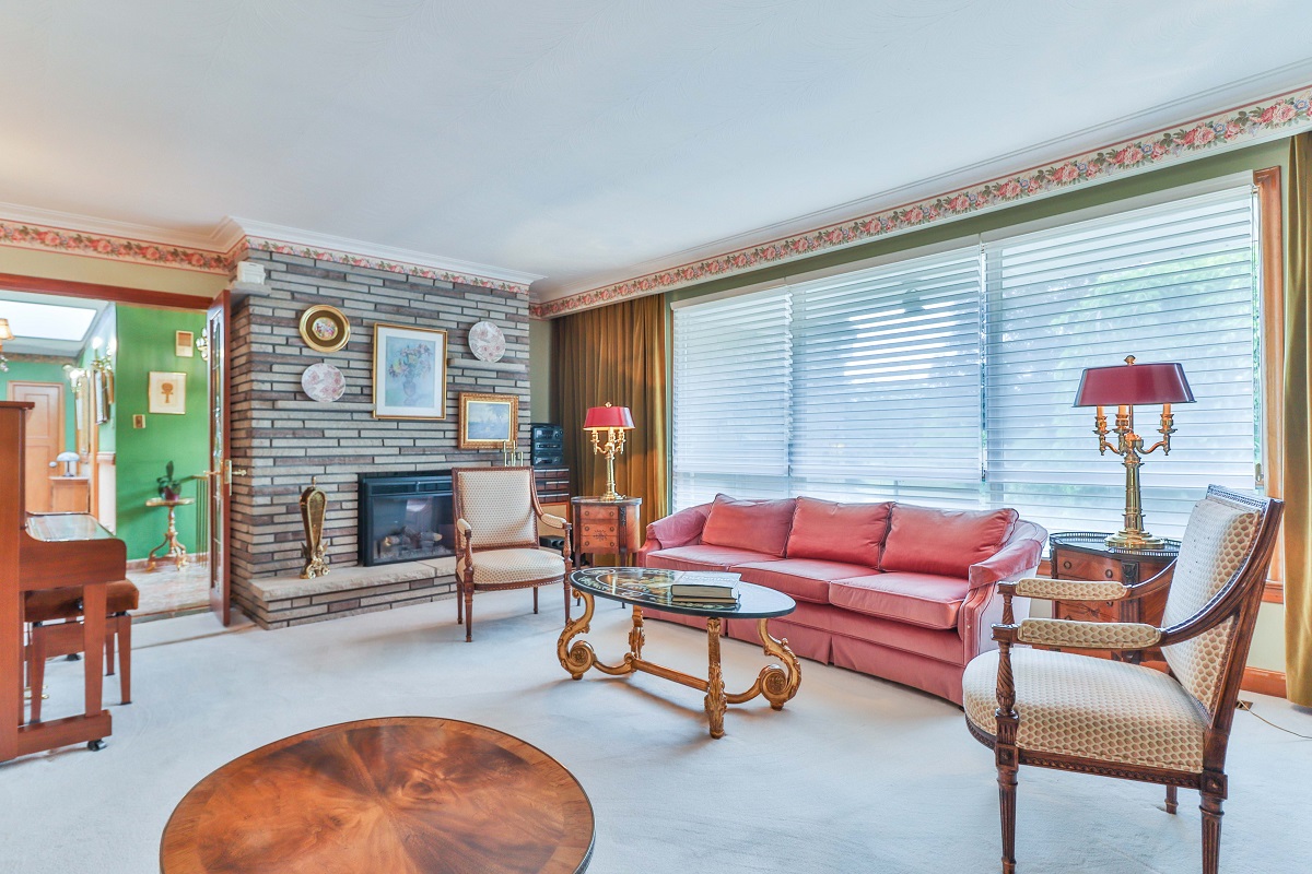 Living room with electric fireplace in brick wall, broadloom carpet and crown moulding.