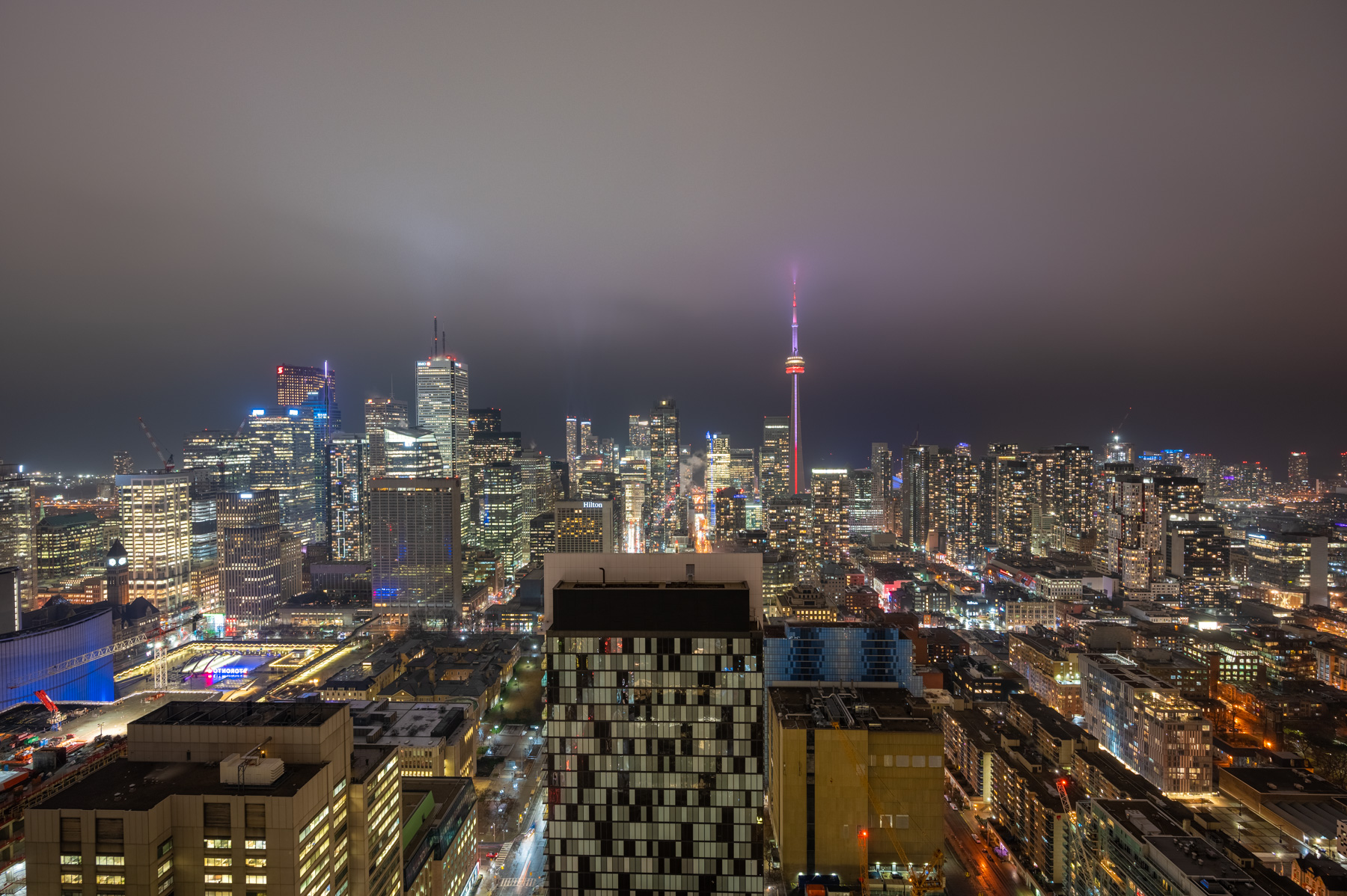 toronto skyline night cn tower glowing red purple city lights Toronto skyline at night with CN Tower glowing red and purple.