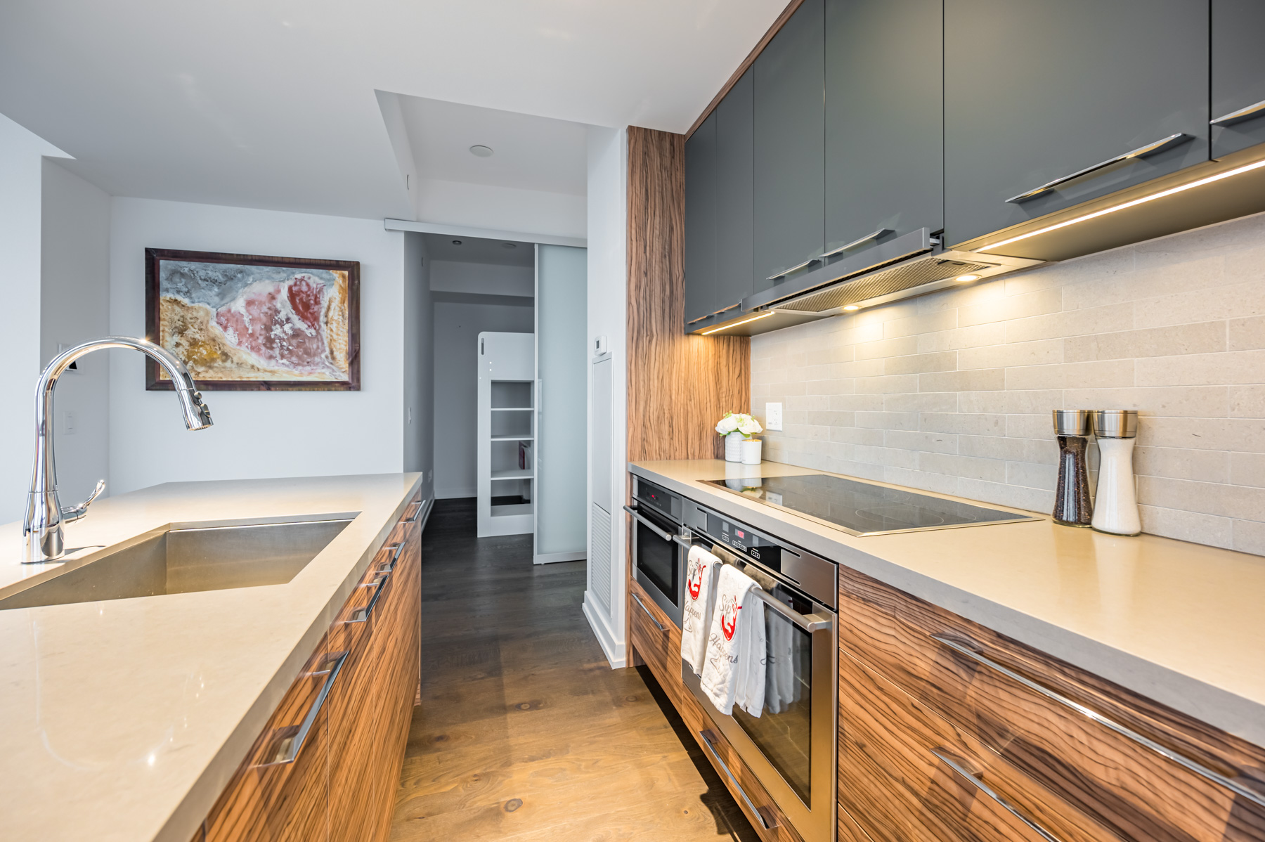 Condo kitchen with black cupboards, shiny cabinets, granite back-splash and marble counters