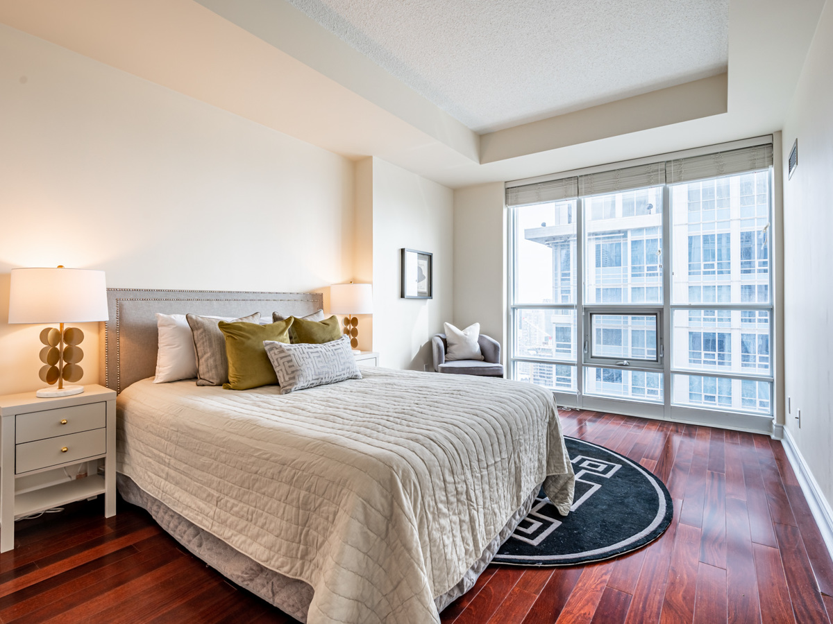 763 bay st unit 4705 spacious master bedroom with bed 763 Bay St Suite 4705 huge master bedroom with queen-sized bed, armchair and side tables.