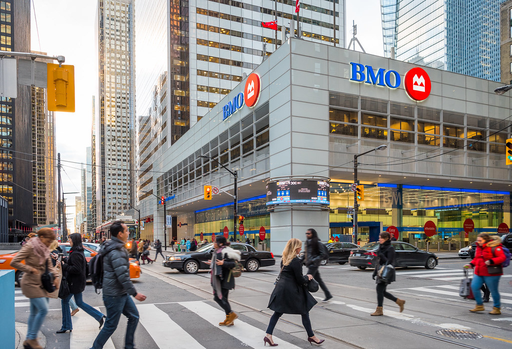 pedestrians crossing street foreground BMO building background Pedestrians crossing street in foreground; BMO building in background.