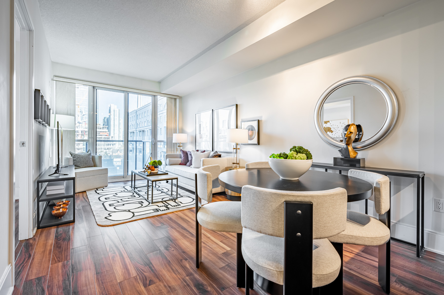 Brightly lit condo dining room and living room with view of CN Tower.