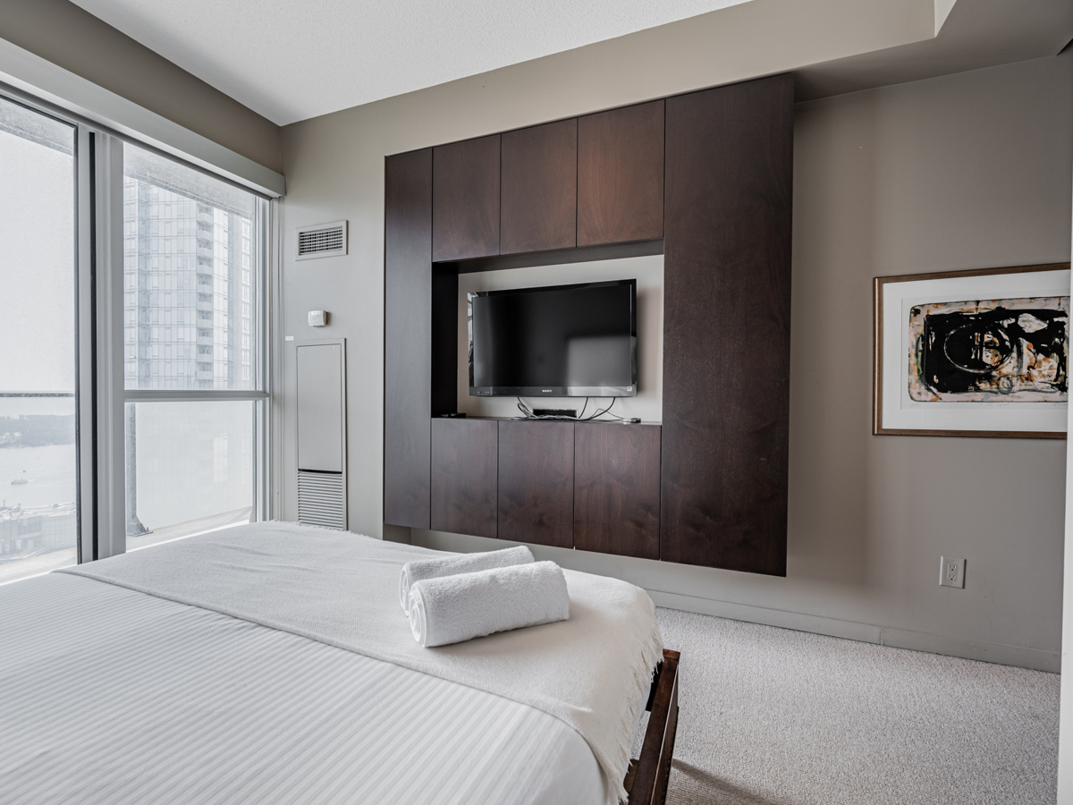 Condo bedroom with clean-looking entertainment centre.