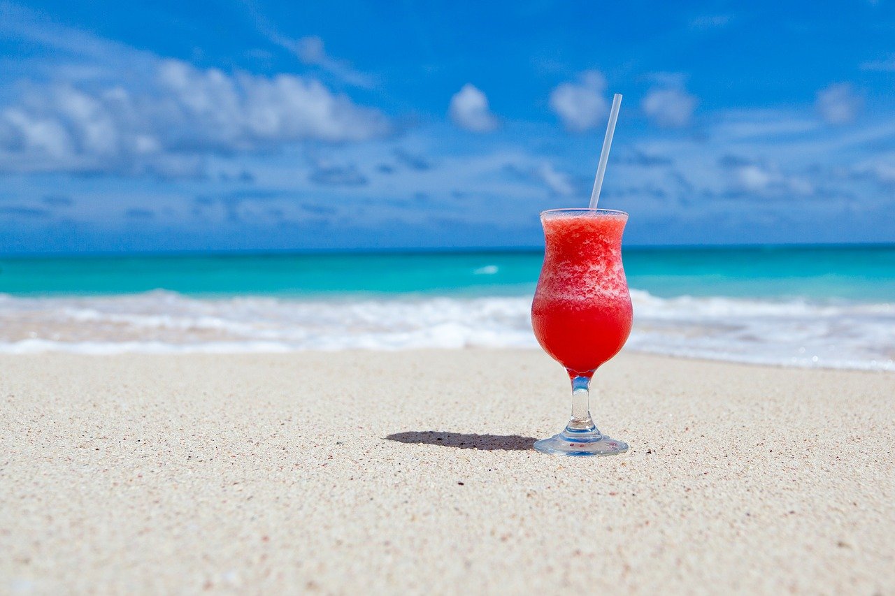 Cocktail glass on sandy beach.