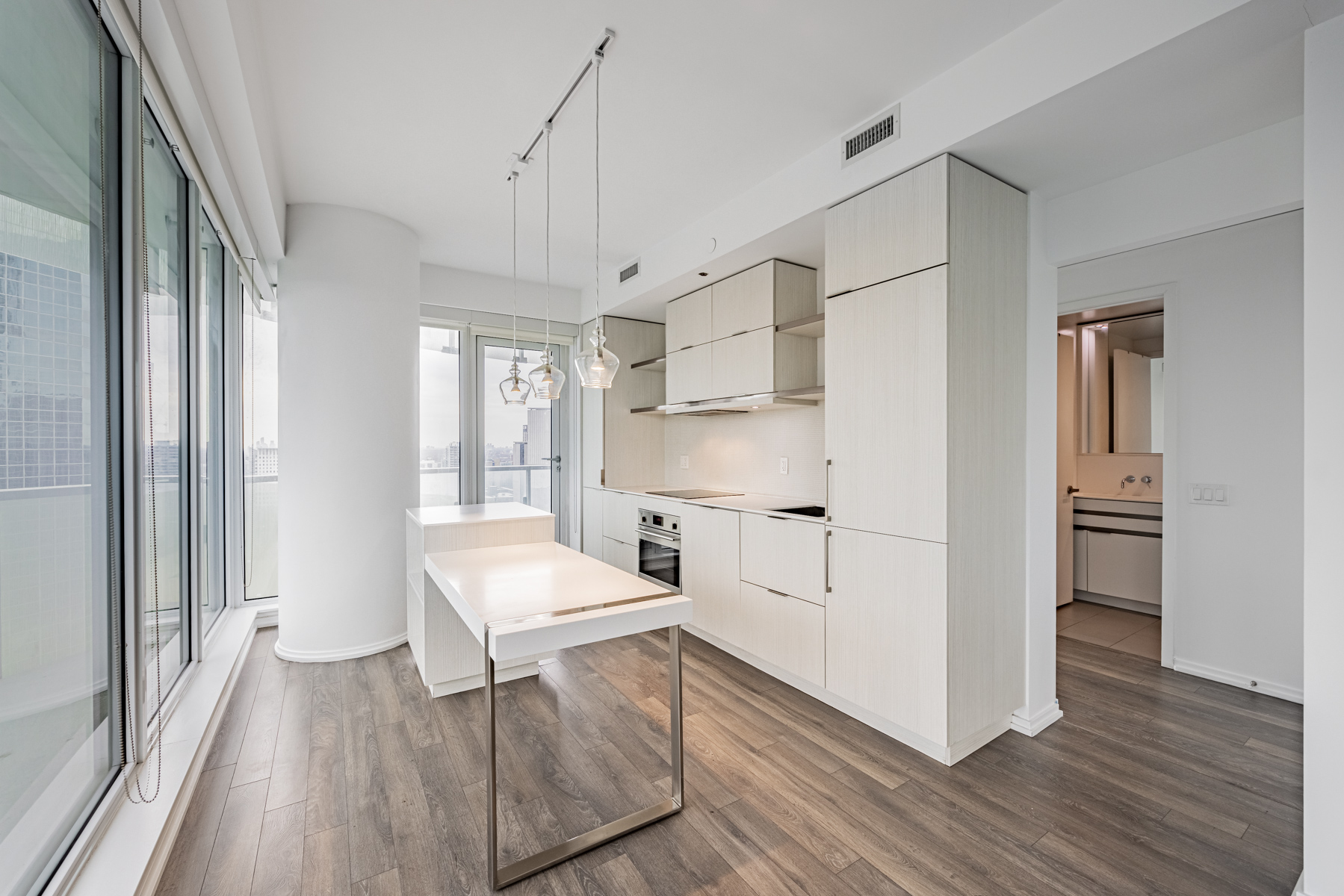 197 Yonge St Unit 2209 kitchen with light-coloured wood cabinets, laminate floors and pendant lights.