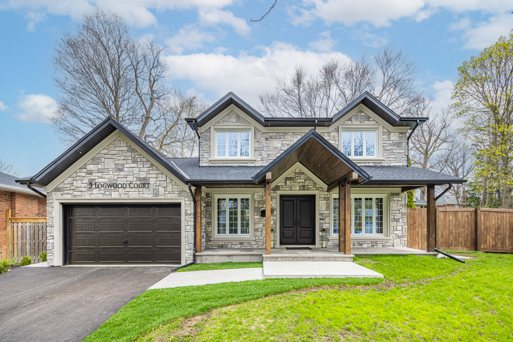 3 Logwood Court gray stone exterior with green lawn, large driveway and 2 car garage.