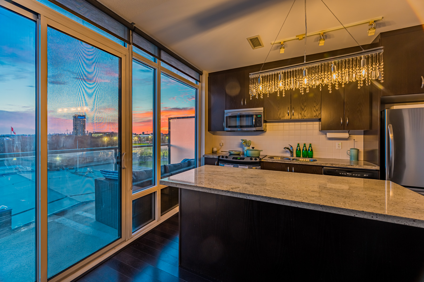 11. kitchen island chandelier Lake Ontario at dusk 90 Stadium Rd Suite 824 Kitchen island with chandelier and view of Lake Ontario at dusk.