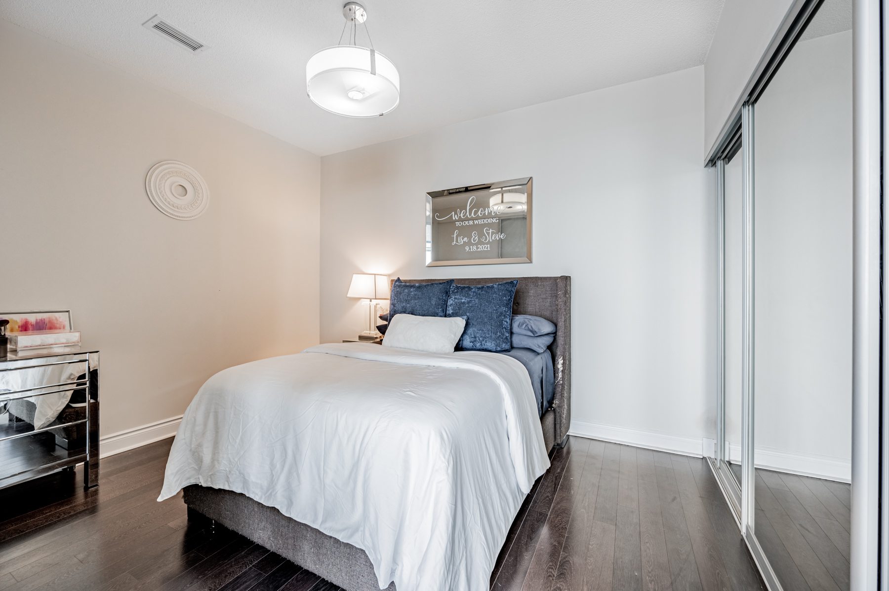 12. Large primary bedroom with LED light 90 Stadium Rd Unit 824 Condo bedroom with dark laminate floors and circular ceiling lamp – 90 Stadium Rd Unit 824.