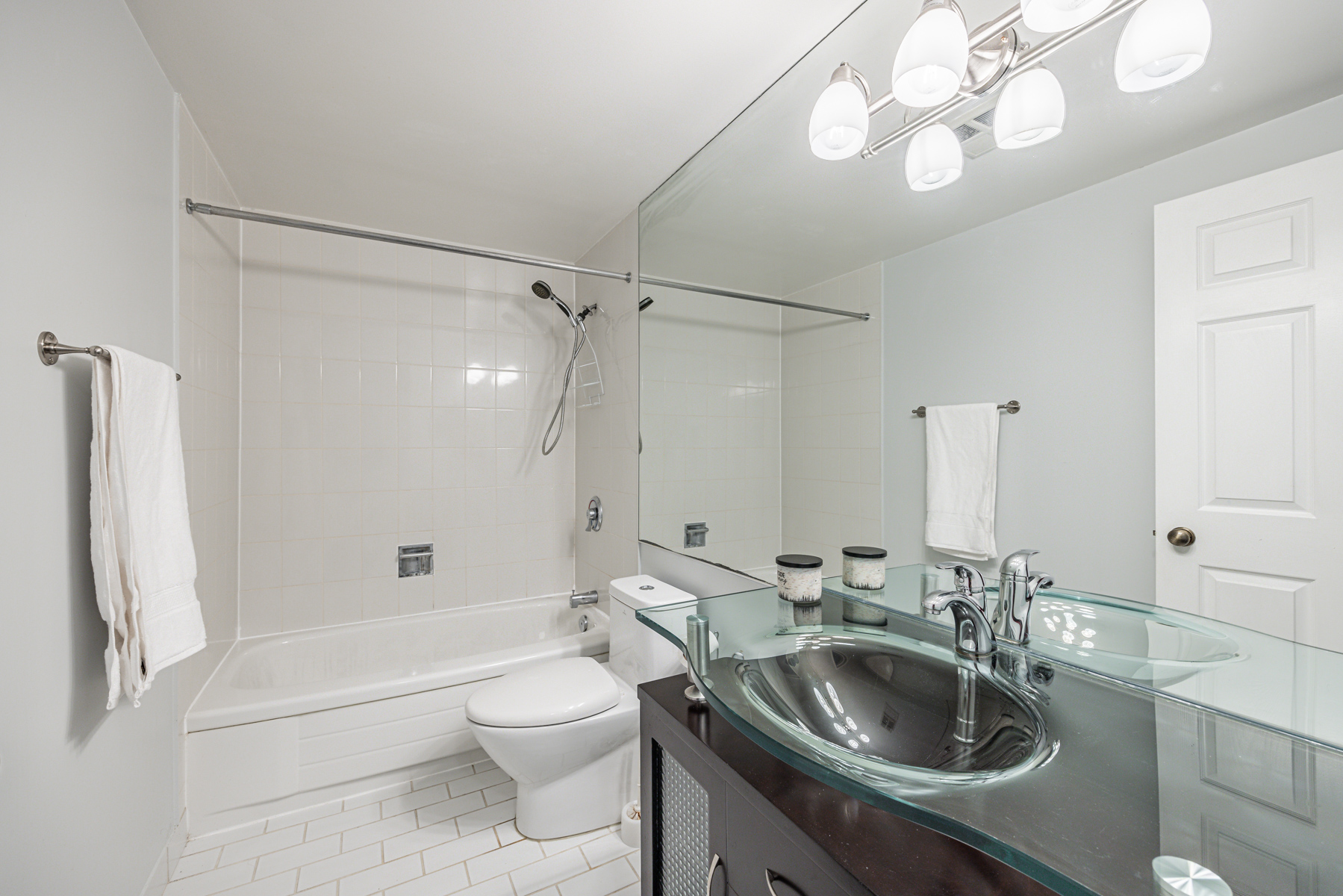 Bathroom with white tiles, long mirror & soaker tub – 88 Charles St E Unit 204.