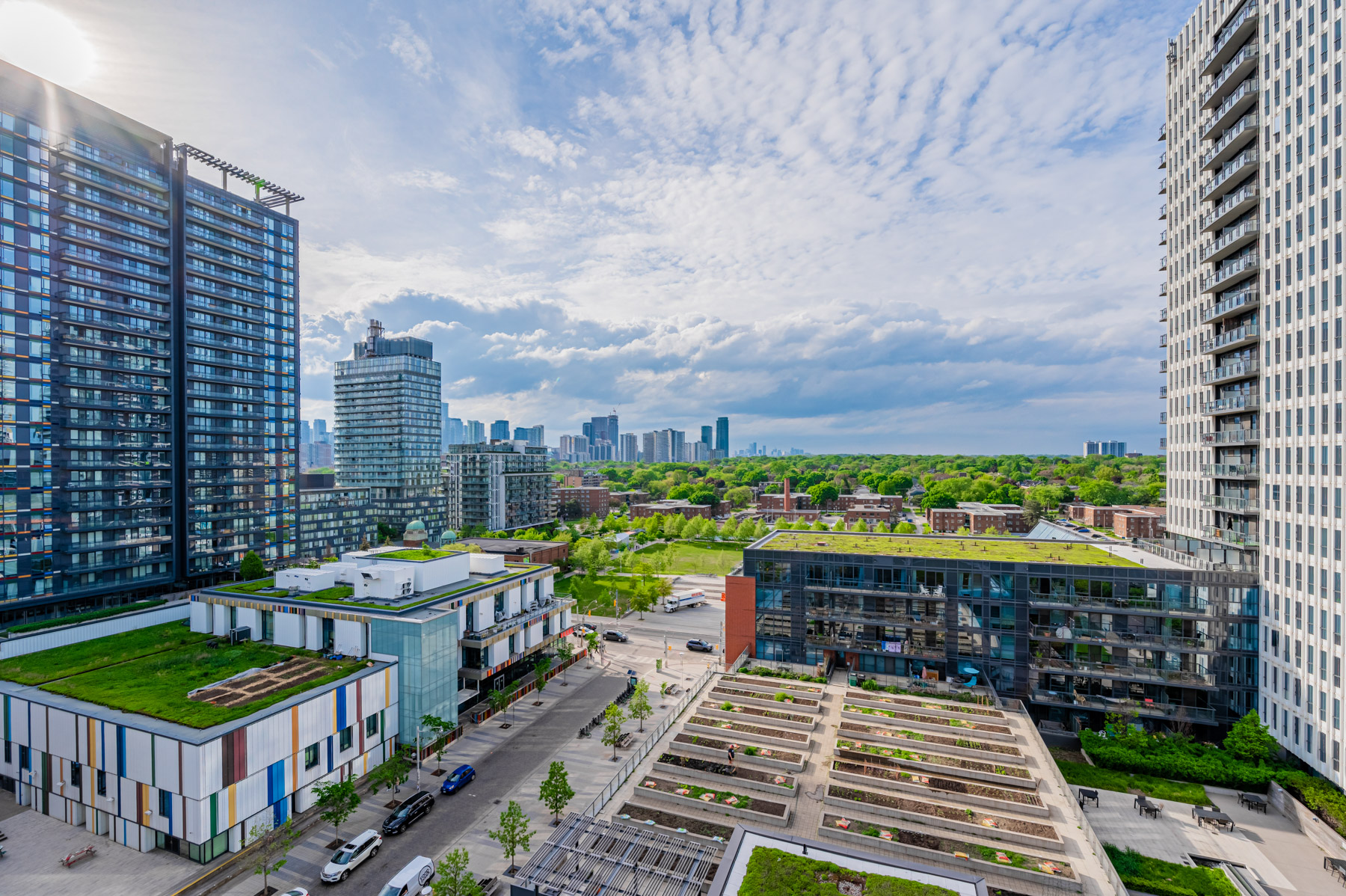 View of lush greenery, blue skies and buildings from 55 Regent Park Blvd Unit 1210.