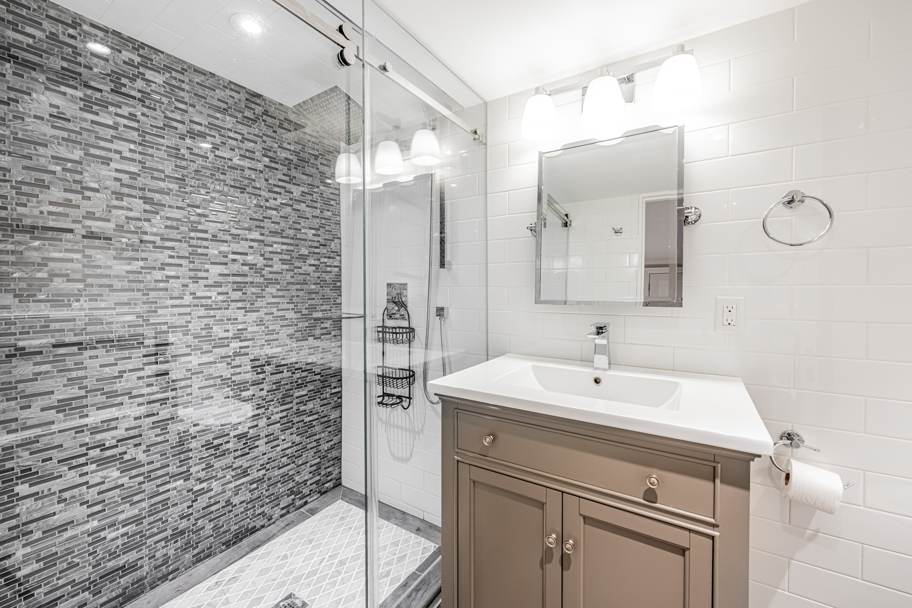 Basement bath with frameless glass door, vanity, intricate tiles and rain shower.