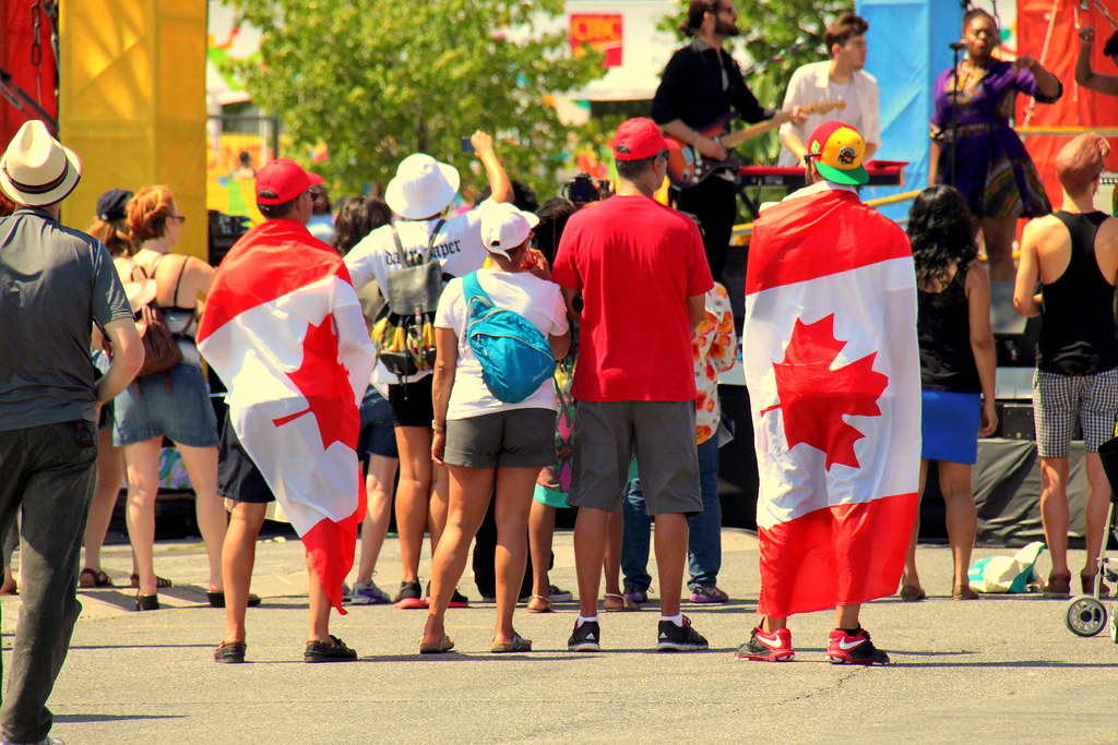 27. people watching concert at Canadian National Exhibition People wrapped in Canadian flags watching concert at Canadian National Exhibition.