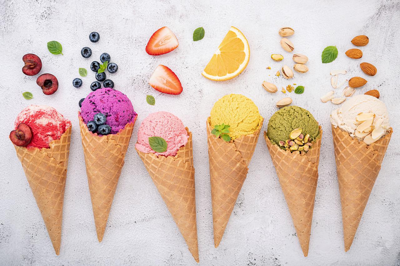 Colourful ice cream cones with fruit ingredients above.