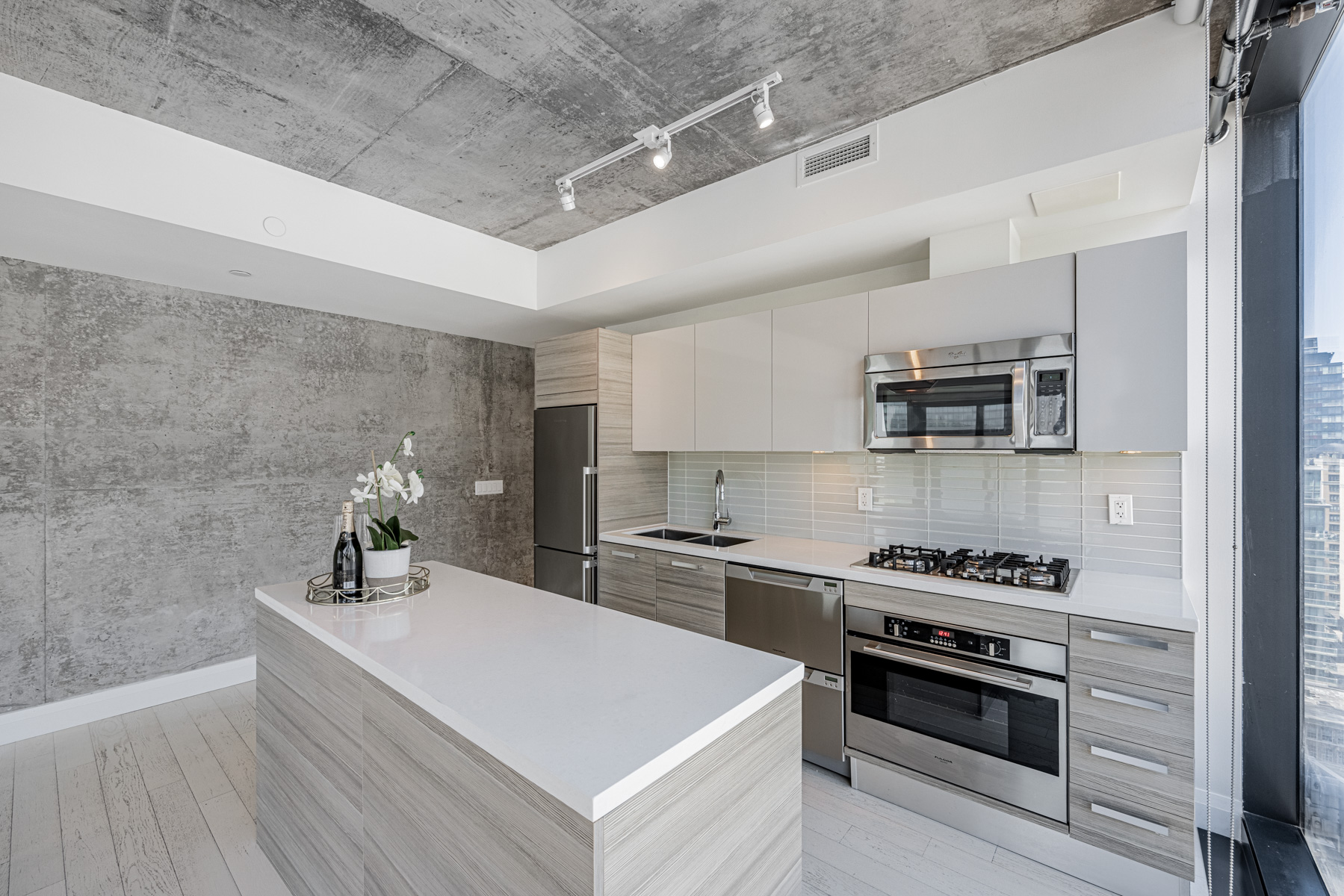 Modern condo kitchen with track lights and under-cabinet lighting.