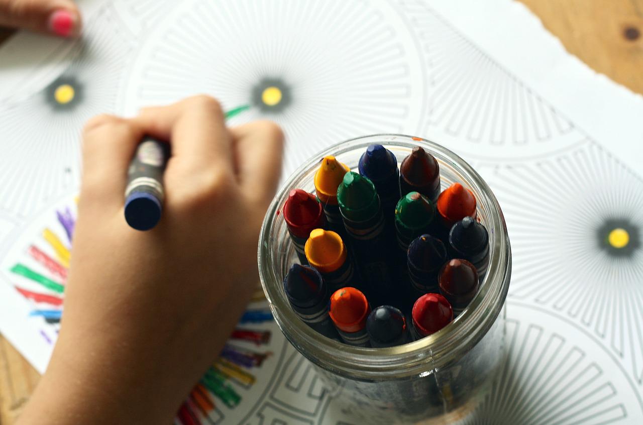 Child colouring picture book with crayons.