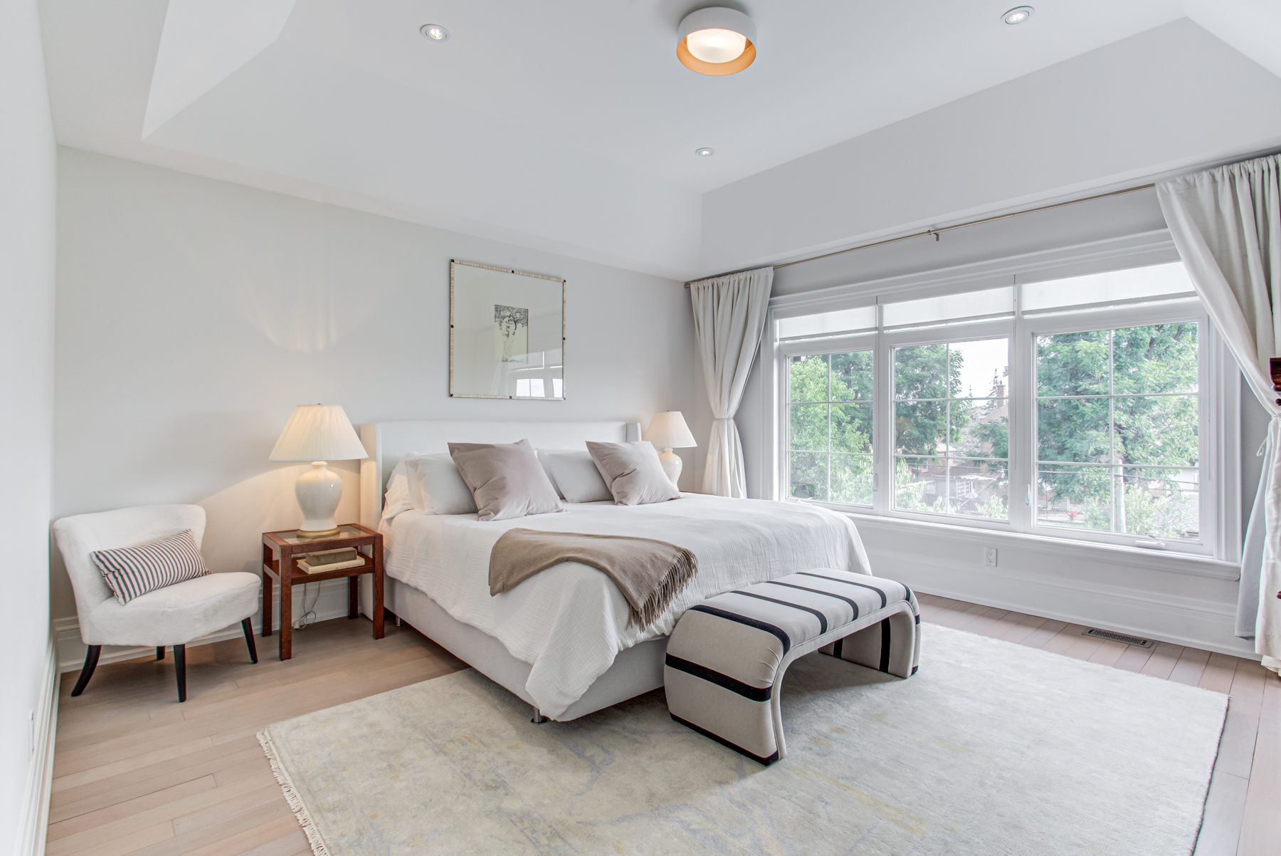 Large primary bedroom with bed, lamps and tables – 741 Glencairn Ave.