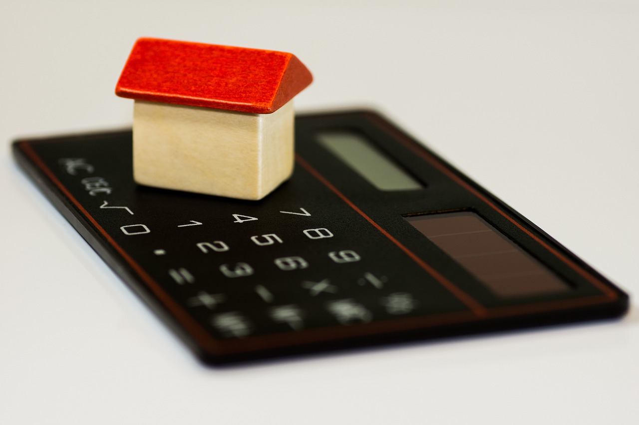 Red toy house on calculator showing credit score calculations.