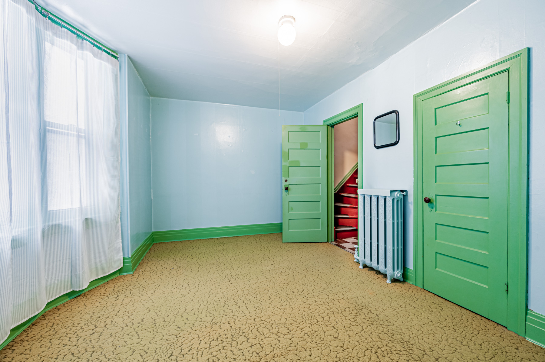27 Granby St primary bedroom with green closet door, blue walls and unfinished floor.