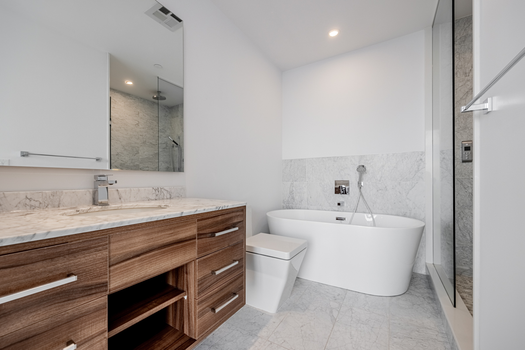 Ensuite bath with stone floors, marble counters and wood cabinets – 488 University Ave Unit 2710.