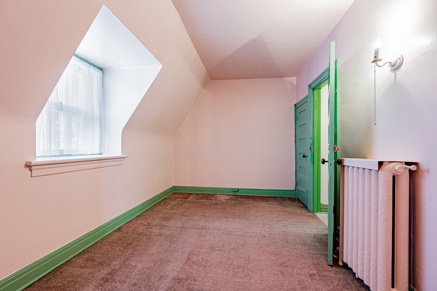 Bedroom with pink walls, carpet and window alcove.