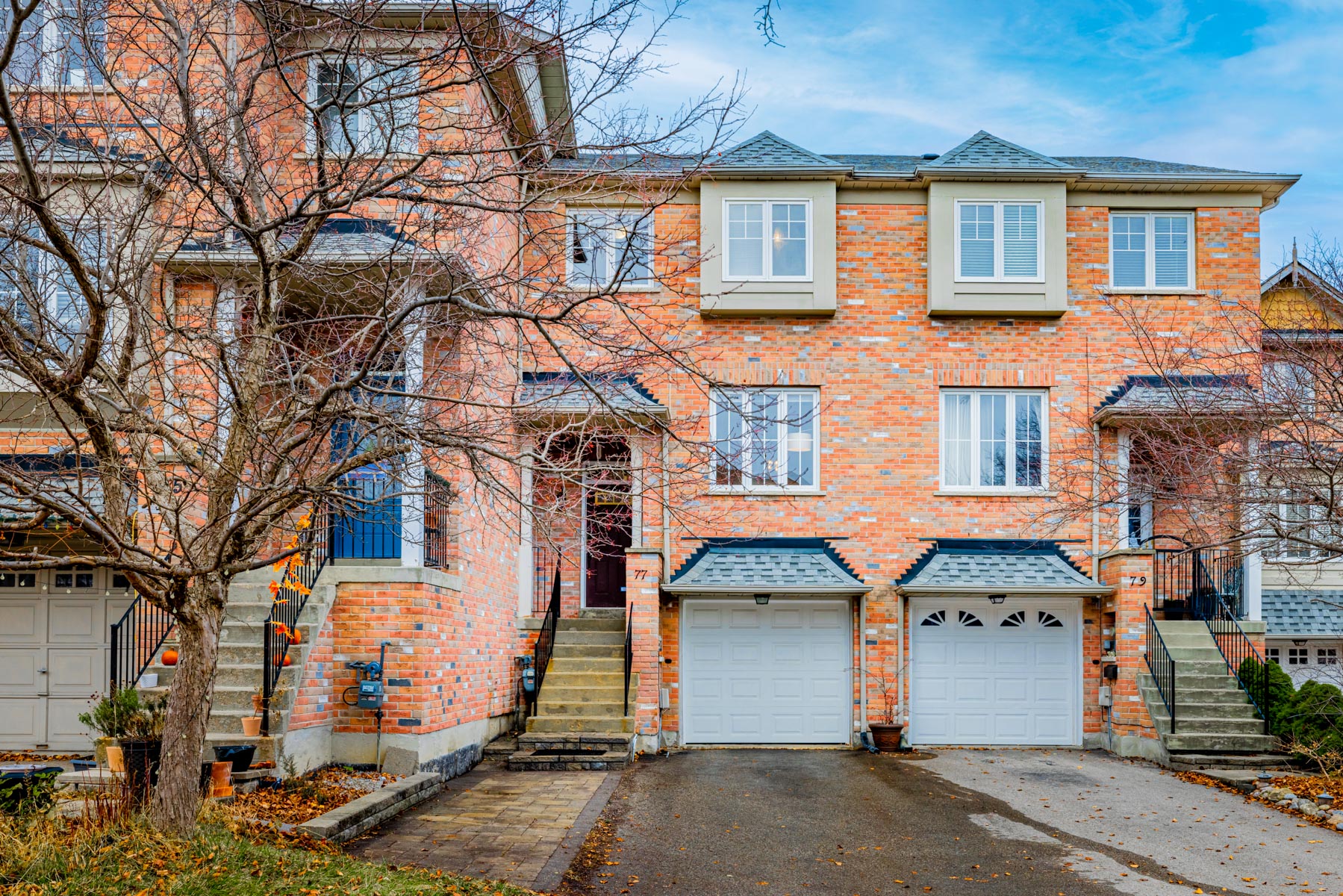 Front of 77 Schouten Cres, a 2-storey townhouse with red-brick facade and square windows.