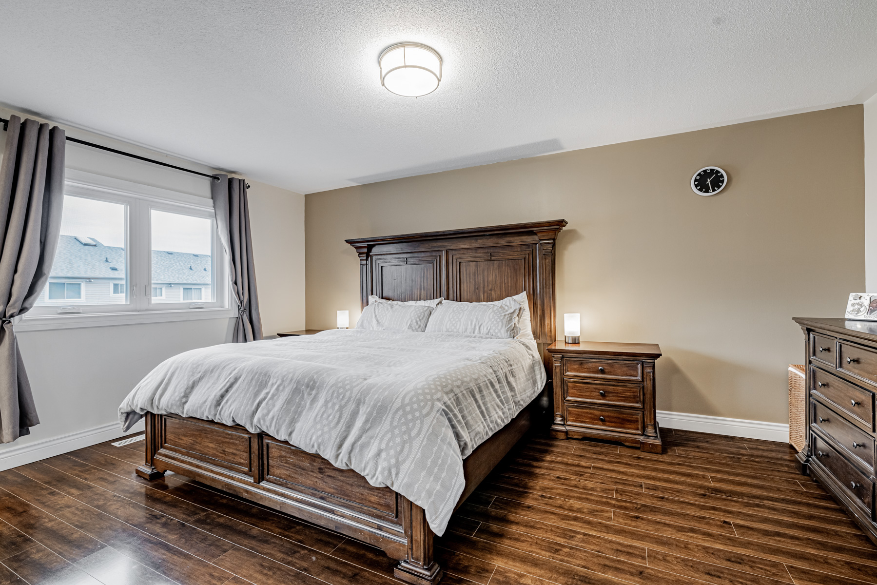 12. Large primary bedroom with dark laminate floors huge bed 77 Schouten Cres 77 Schouten Cres large primary bedroom with dark laminate floors, large bed and beige wall.