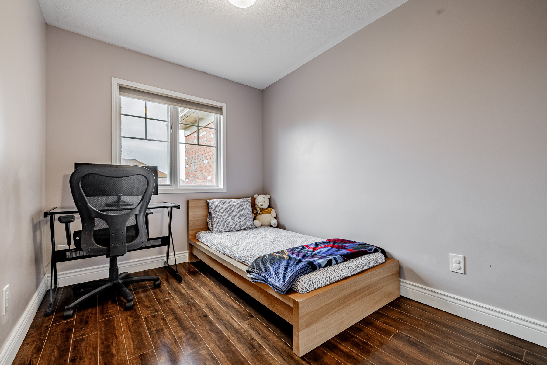 15. 77 Schouten Crescent 2nd bedroom with desk chair bed laminate floors 77 Schouten Cres 2nd bedroom with desk, chair, bed and dark laminate floors.