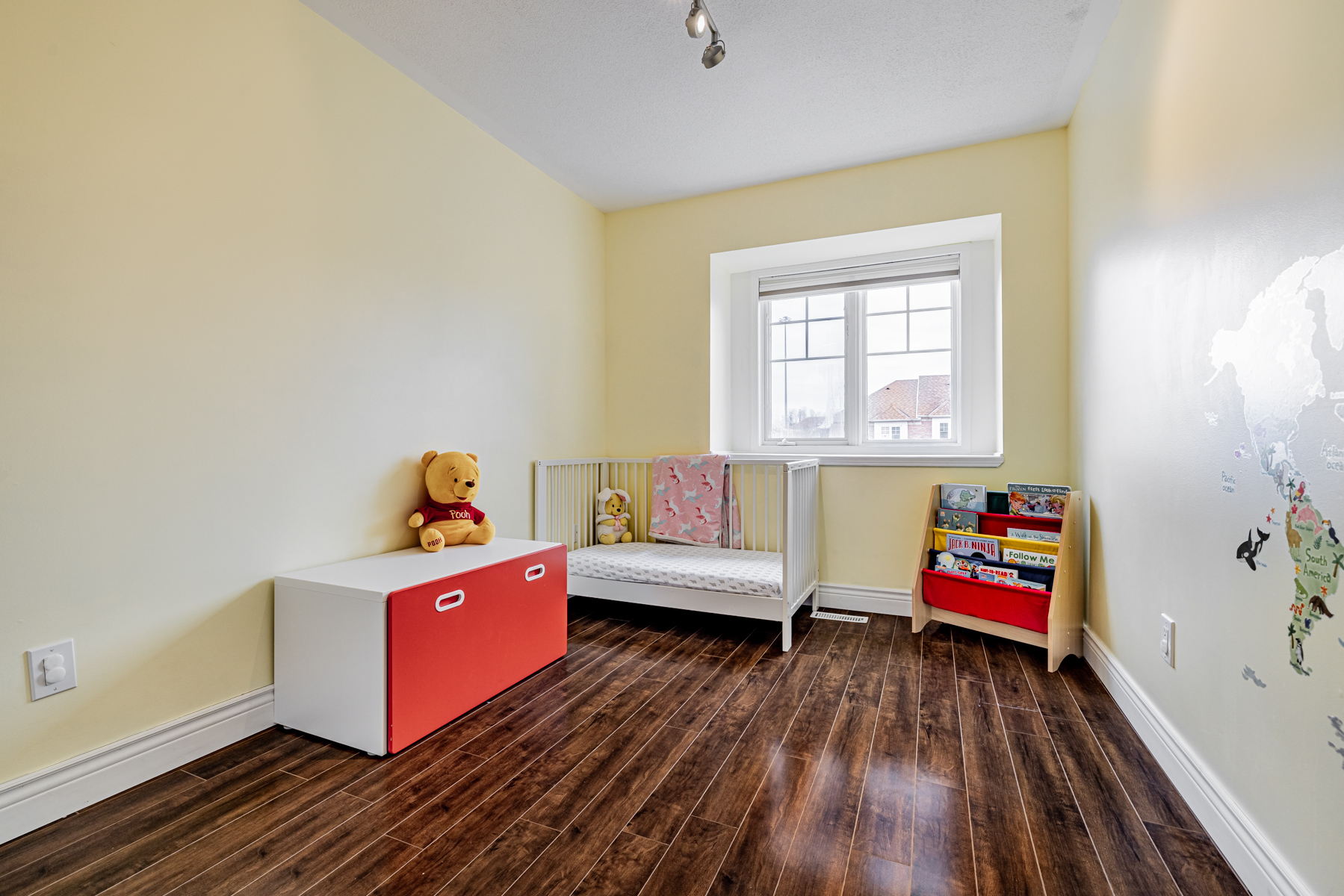 16. Bedroom nursery winnie the poo stuffie bookshelf yellow walls Bedroom nursery with crib, Winnie the Poo stuffy, bookshelf, yellow walls and laminate floors.