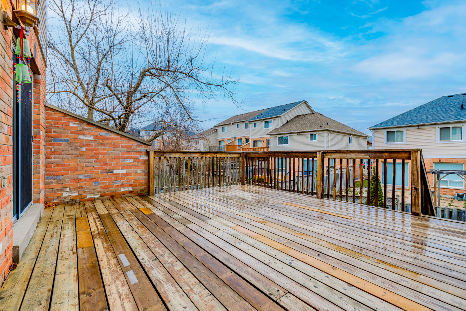 23. 77 Schouten Cres wood deck wet view of houses Large wooden deck wet with rain and view of houses.